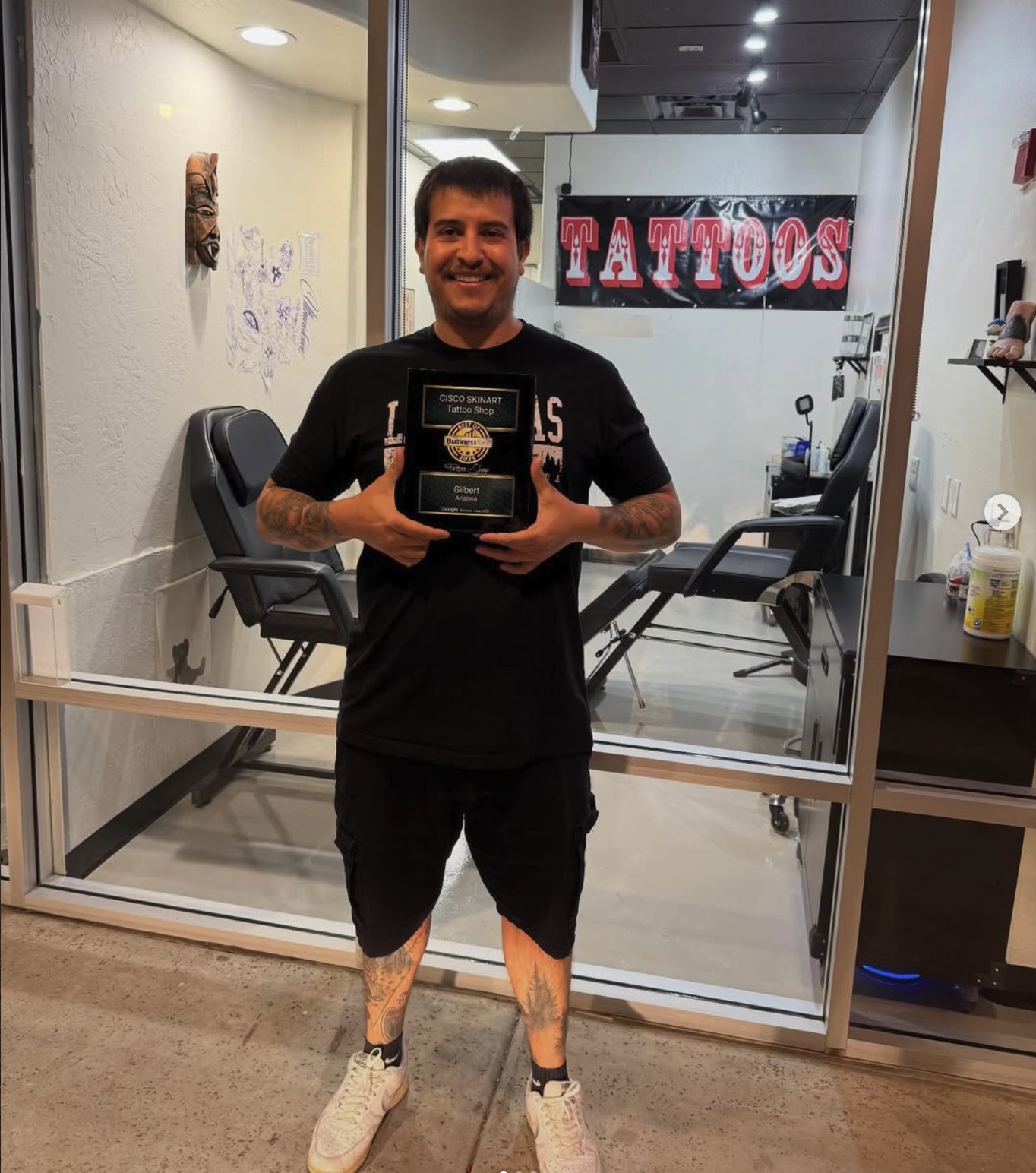 Cisco, owner and artist of Cisco Skinart, holding a Best of Business award inside the Gilbert studio